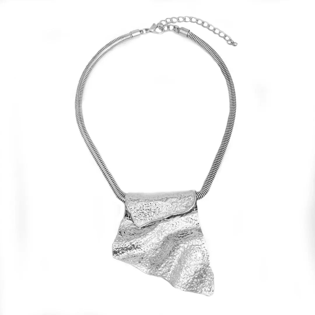 Architectural silver pendant necklace with a sculptural folded metal design. Intentional jewelry crafted to anchor a woman's wardrobe.